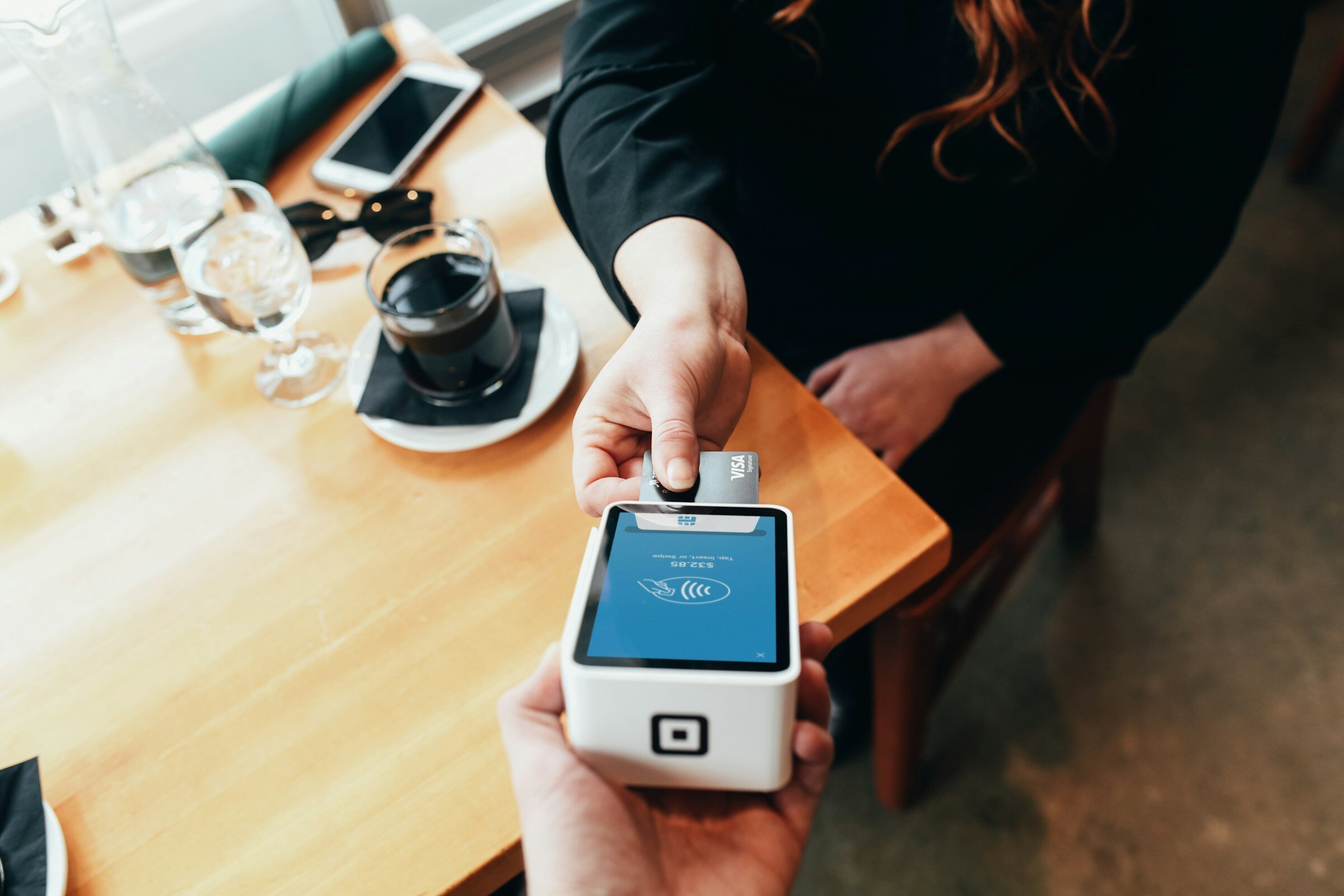 A person in a cafe makes a payment into an electronic card machine